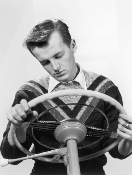 circa 1950:  Studio portrait of a young man sleeping at a steering wheel.  (Photo by Lambert/Getty Images)
